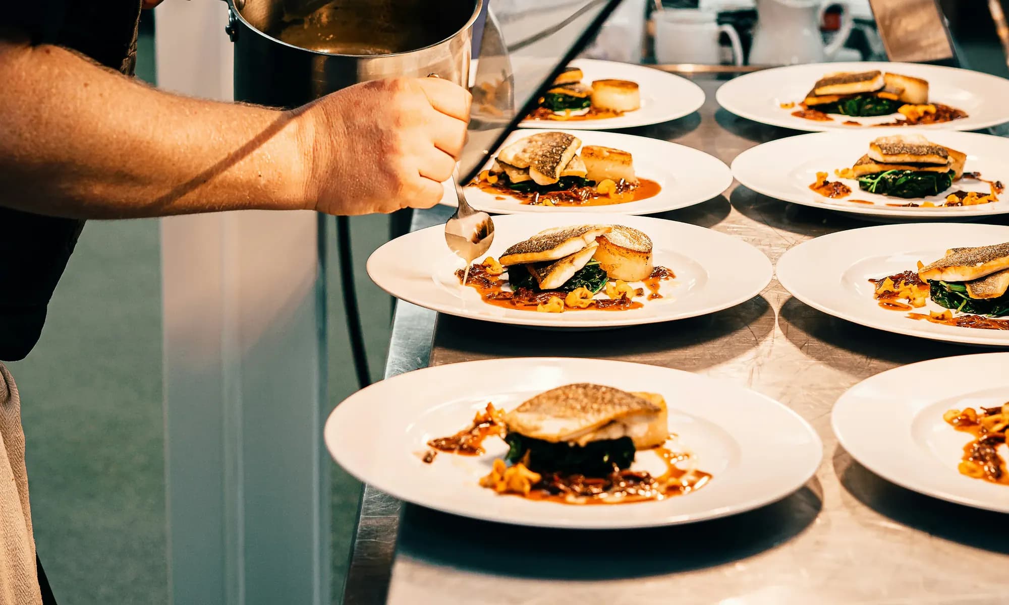 A chef finishing plates at the pass