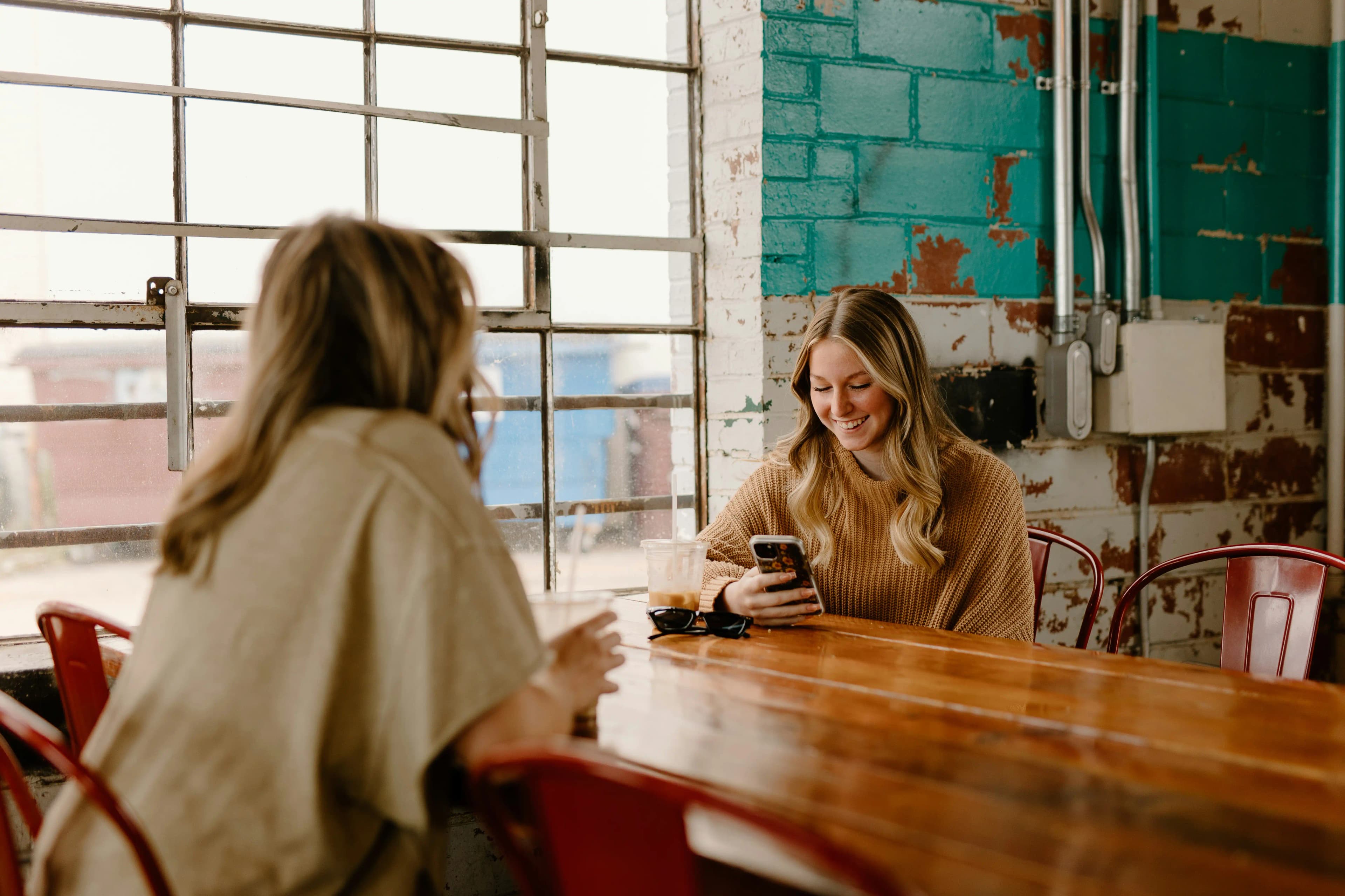 Due amiche al tavolo di un bar, una controlla i suoi premi